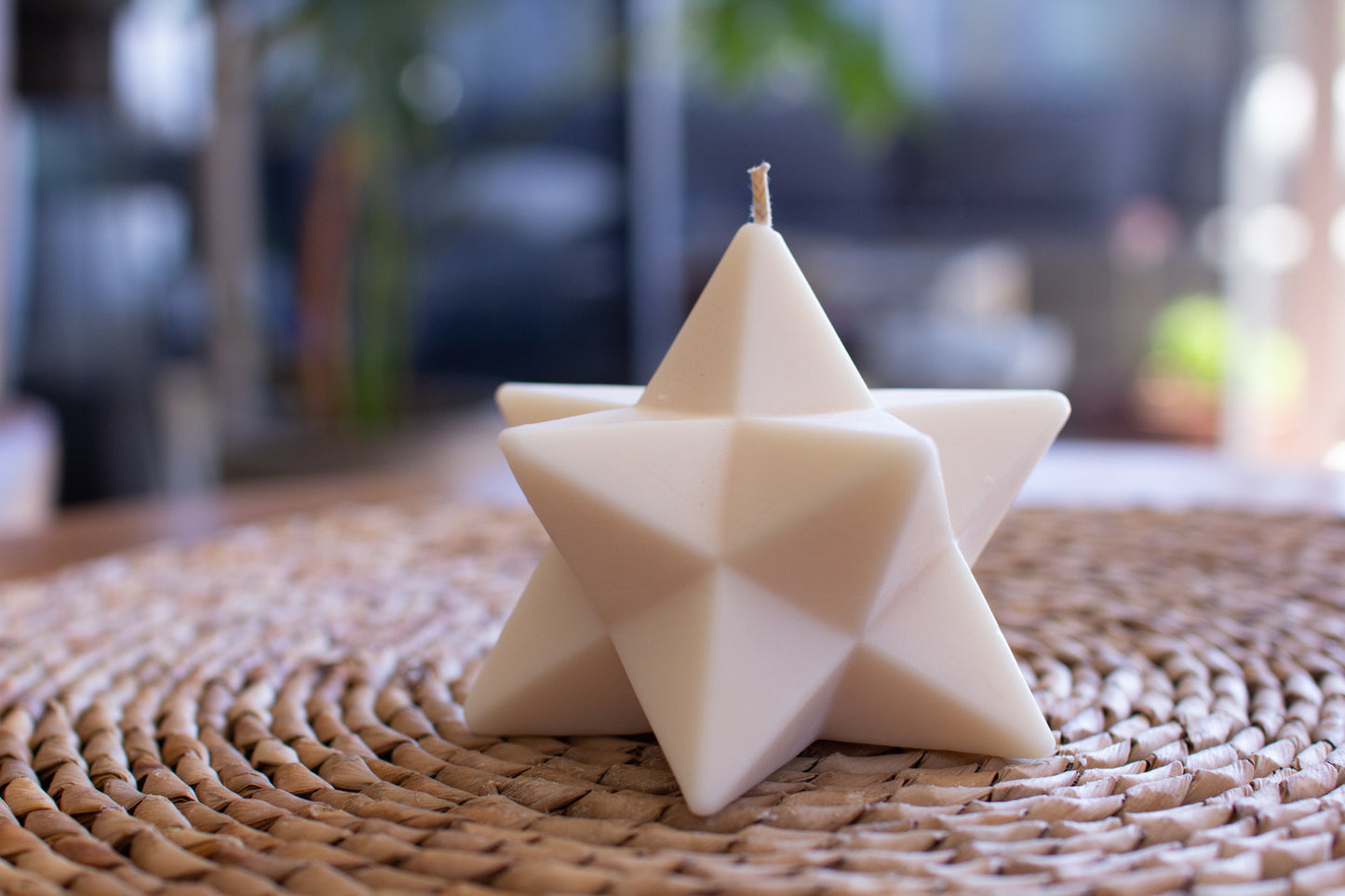 Star-shaped candle on a woven mat with a blurred indoor background