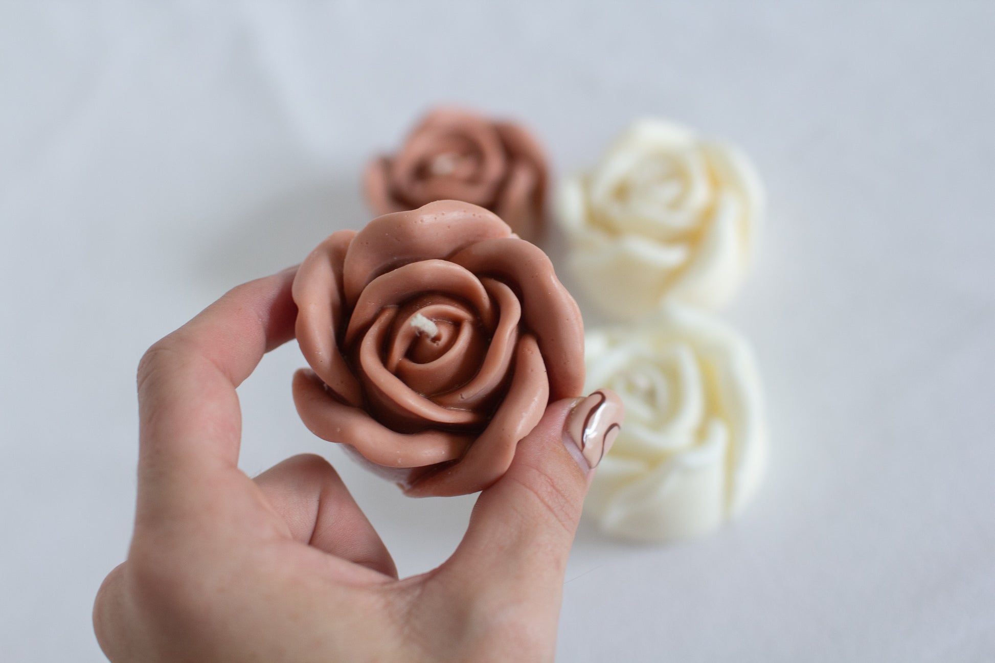 Hand holding rose shaped candle to show size context