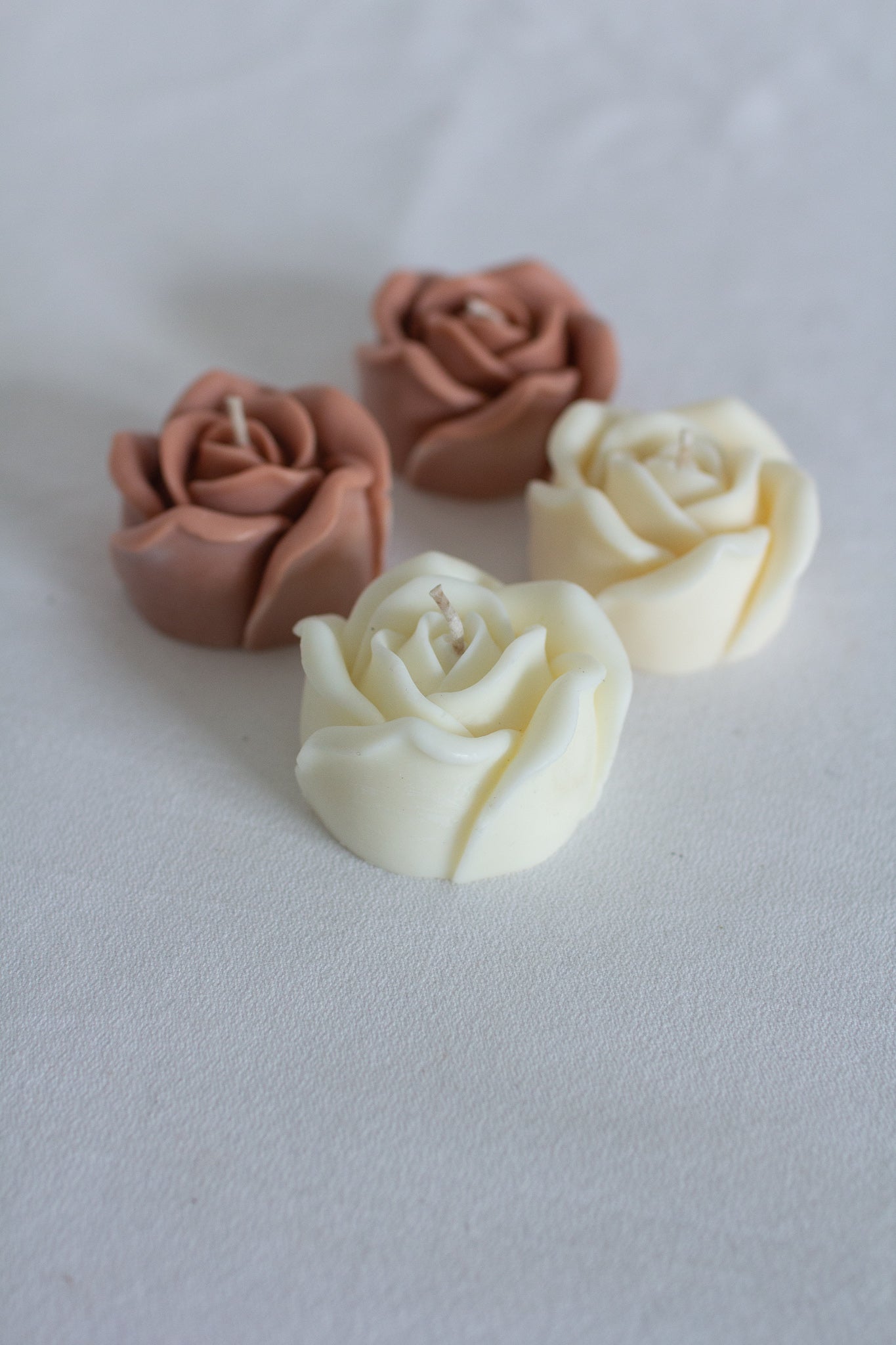 4 rose shaped candles on white background